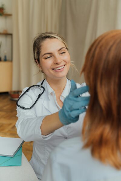 Home A cheerful healthcare professional examining a patient indoors, promoting positive healthcare experiences.