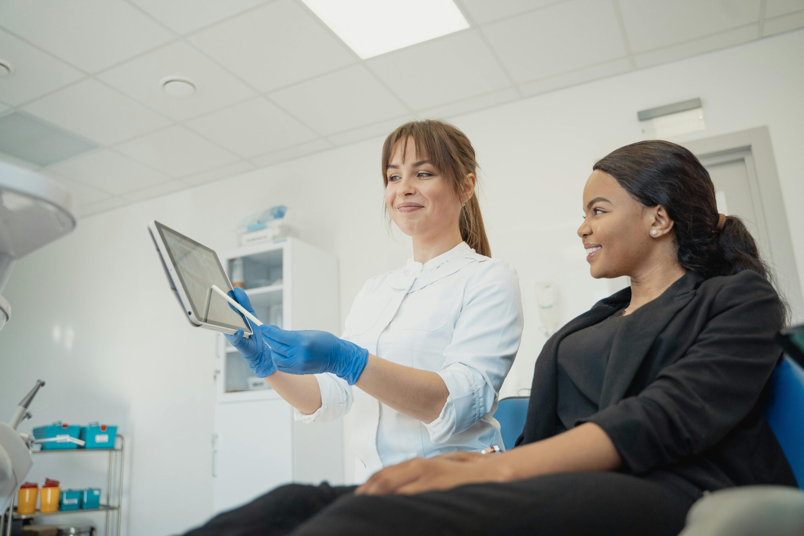 Home Dentist and patient discussing treatment plan using a tablet in a modern clinic setting.